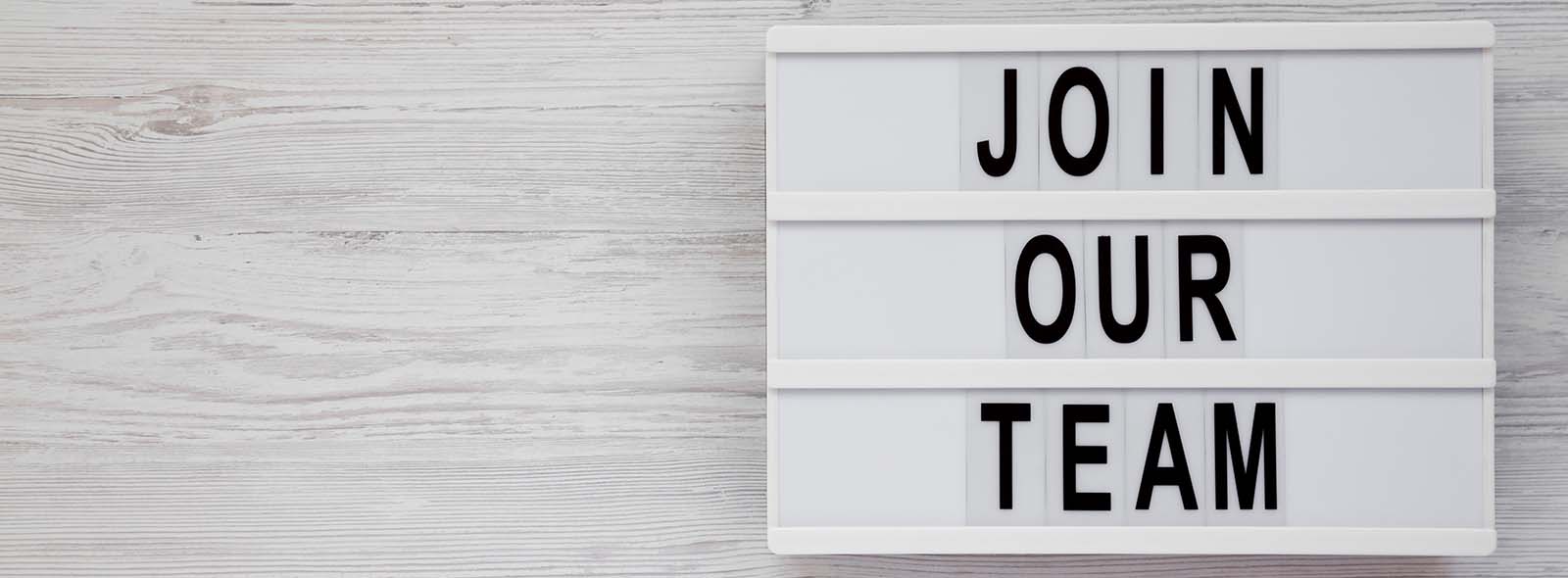 'Join our team' words on a lightbox on a white wooden background